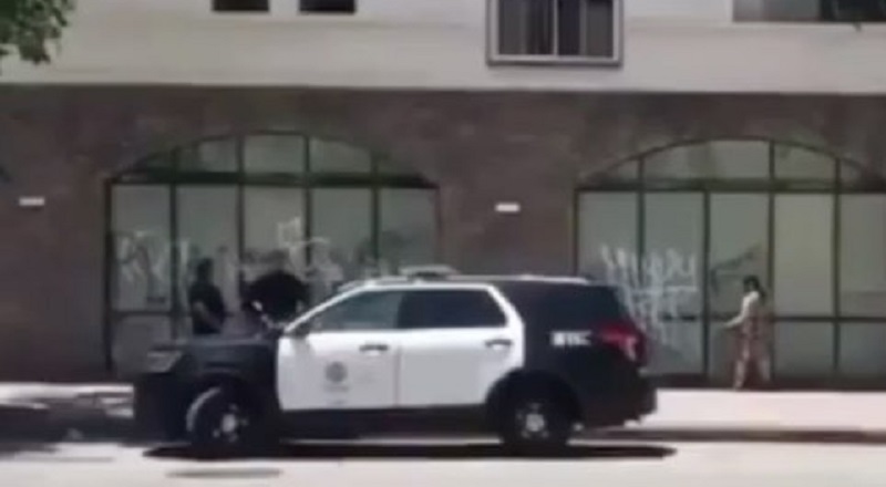 White woman vandalizes a building, in Los Angeles. Three LAPD officers are seen watching her, even holding a conversation with her. To make matters worse, they even laugh, as she is spray-painting the building.