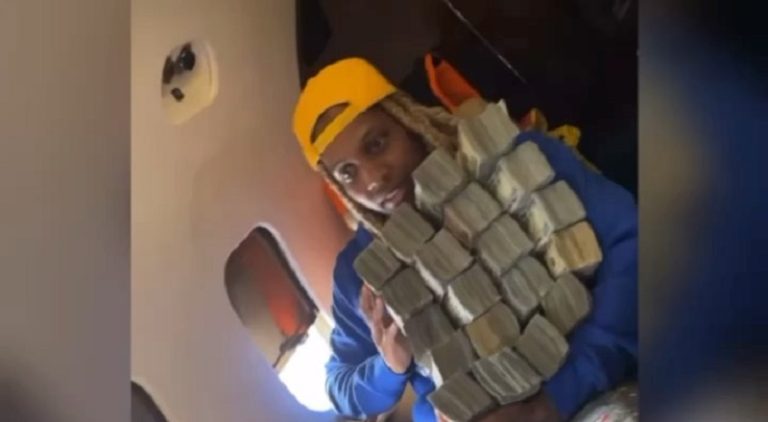 Lil Durk holds a pile of cash so large that it's falling over