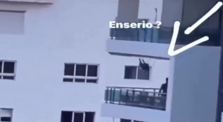 Child swings on makeshift swing going over tall building balcony