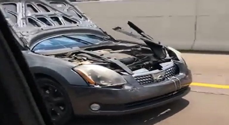 Man drives car with hood covering the windshield