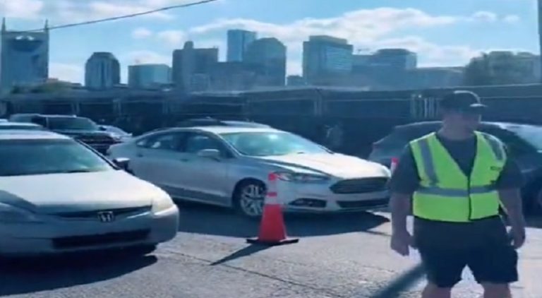 Man wears safety vest to stop traffic so his friends can leave