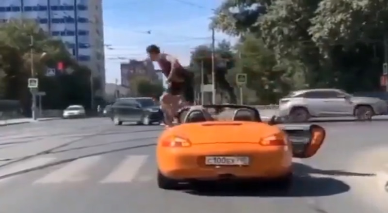 Man opens car door and walks on top of car to cross street